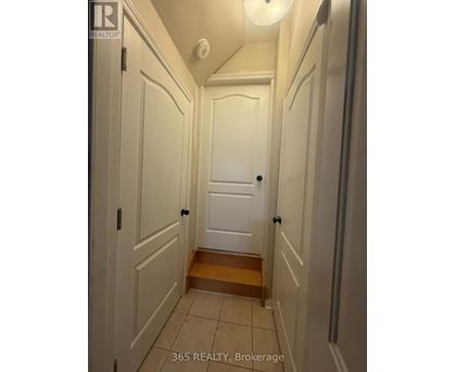 A hallway with white doors and a wooden step.