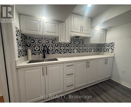 A kitchen with white cabinets and a black and white backsplash.