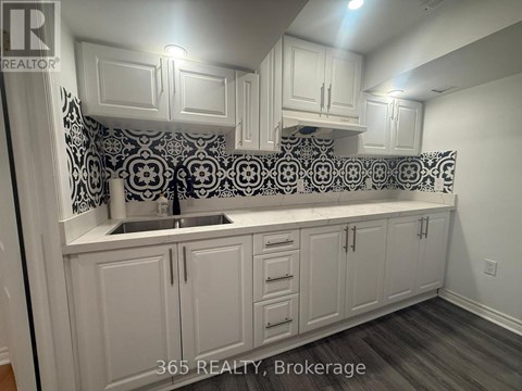 A kitchen with white cabinets and a black and white backsplash.