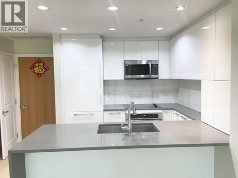 A modern kitchen with a grey countertop and white cabinets.