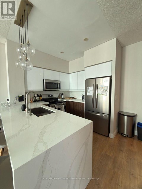 A modern kitchen with a white marble countertop and stainless steel appliances.