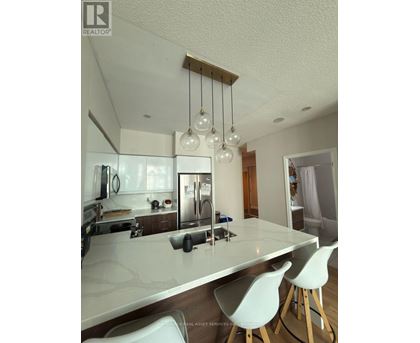A modern kitchen with white cabinets and a marble countertop.