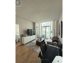 A living room with a flat screen TV and a large window.