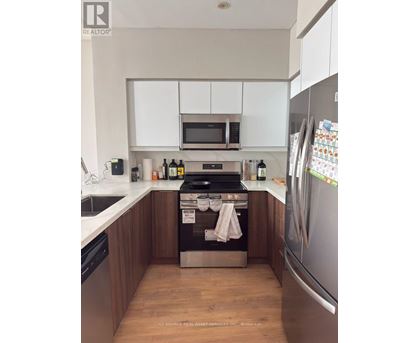 A kitchen with a refrigerator, sink, and cabinets.
