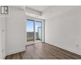 A spacious room with a sliding glass door leading to a balcony.
