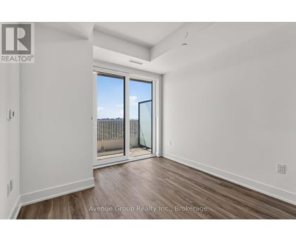 A spacious room with a sliding glass door leading to a balcony.