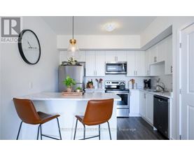 A modern kitchen with a white countertop and brown chairs.