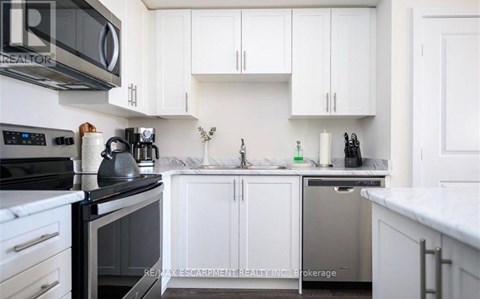 A kitchen with white cabinets and a black stove top.