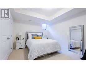 A bedroom with a white bed, a white nightstand, and a white dresser.