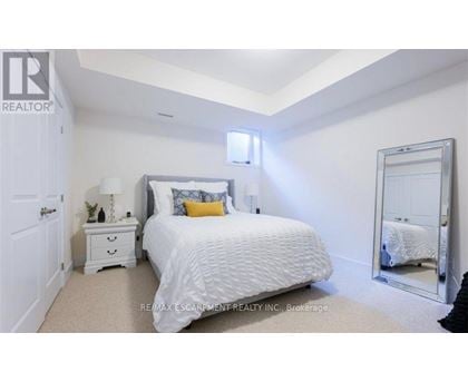 A bedroom with a white bed, a white nightstand, and a white dresser.
