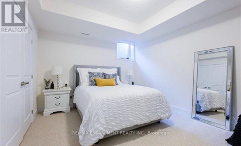 A bedroom with a white bed, a white nightstand, and a white dresser.