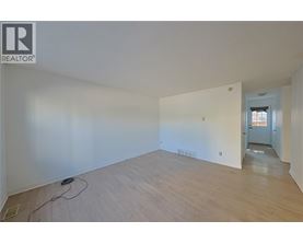 A room with wooden flooring and white walls, with a doorway leading to another room.