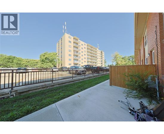 A view of a residential area with apartment buildings, a sidewalk, and a parked car.