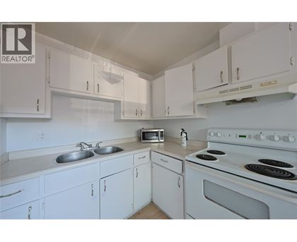 A white kitchen with a stove and microwave.