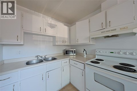 A white kitchen with a stove and microwave.