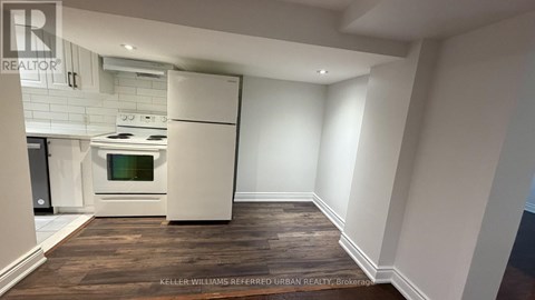 A modern kitchen with white appliances and a wooden floor.