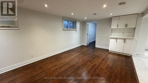 A spacious room with wooden flooring and white walls.