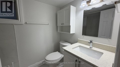 A bathroom with a toilet, sink, and mirror.