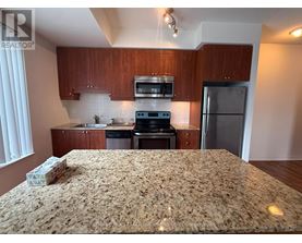 A kitchen with a granite countertop and wooden cabinets.