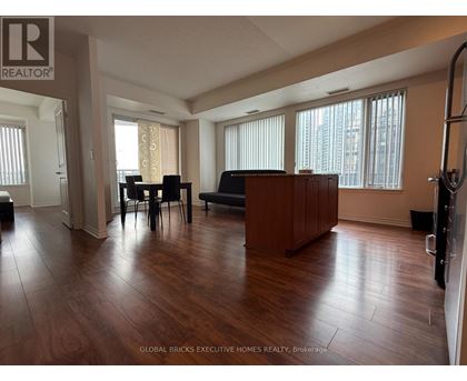A living room with a brown couch and a dining table with chairs.