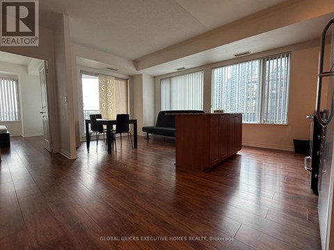 A living room with a brown couch and a dining table with chairs.