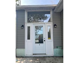 A grey house with a white door and a sign on it.