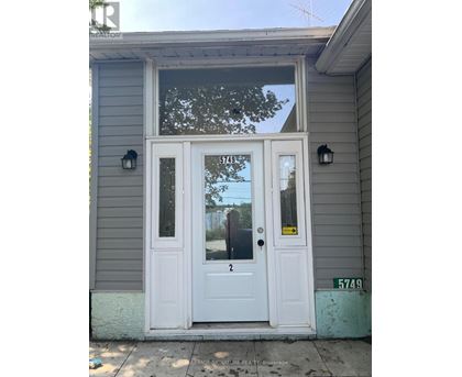 A grey house with a white door and a sign on it.