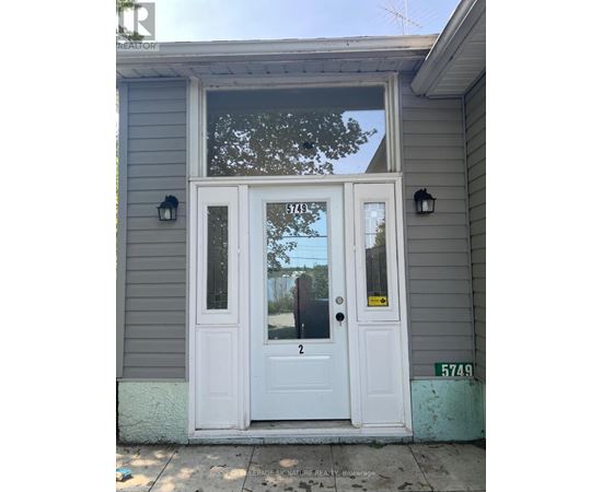 A grey house with a white door and a sign on it.