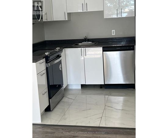 A kitchen with white cabinets and a black countertop.