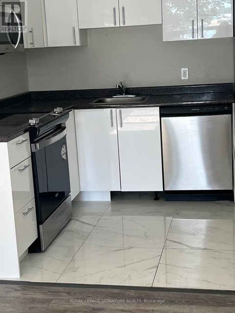 A kitchen with white cabinets and a black countertop.