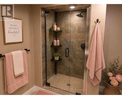 A bathroom with a glass shower stall and a pink towel.