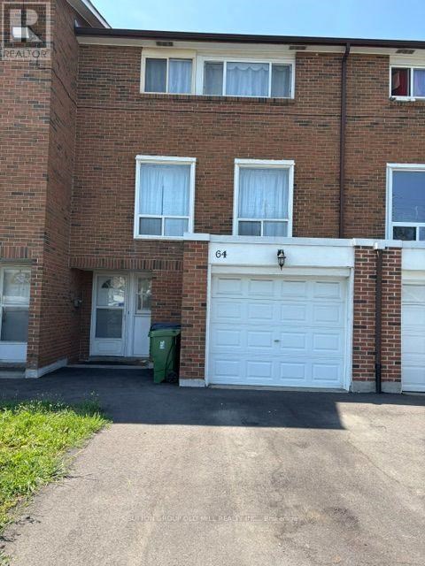A brick building with a white garage door and a green trash can in front.