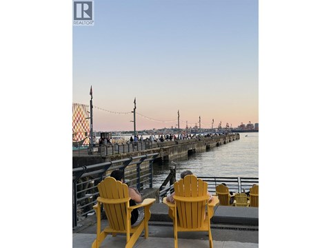 Two yellow chairs are on a dock with a pier in the background.