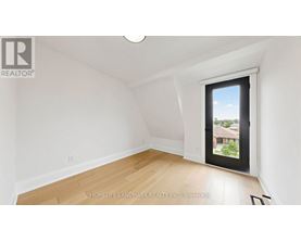A room with a window that has a view of a house and trees outside.