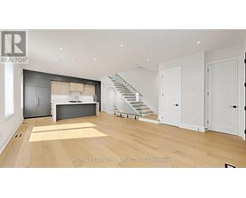 A spacious living room with a staircase leading to the upper floor.