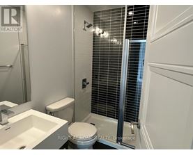 A white toilet in a bathroom with a sink and a shower.