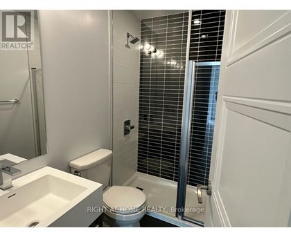 A white toilet in a bathroom with a sink and a shower.