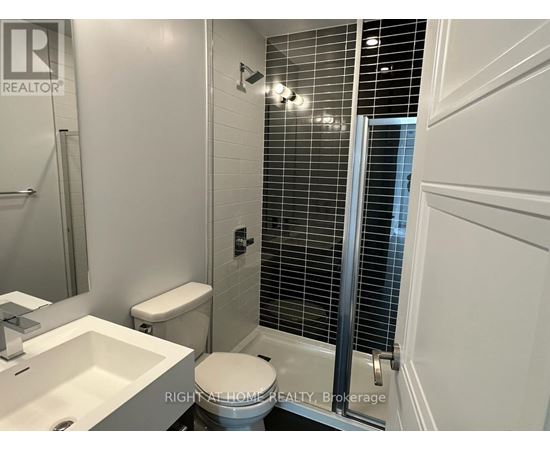 A white toilet in a bathroom with a sink and a shower.