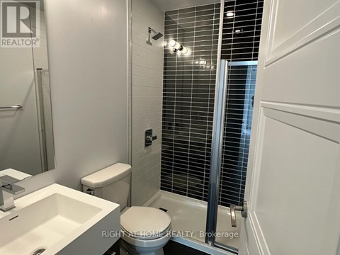 A white toilet in a bathroom with a sink and a shower.