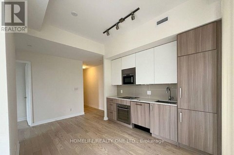 A modern kitchen with wooden cabinets and a microwave above the stove.