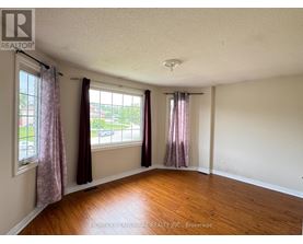 A room with wooden floors and two windows with curtains.
