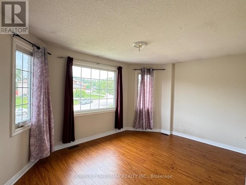 A room with wooden floors and two windows with curtains.