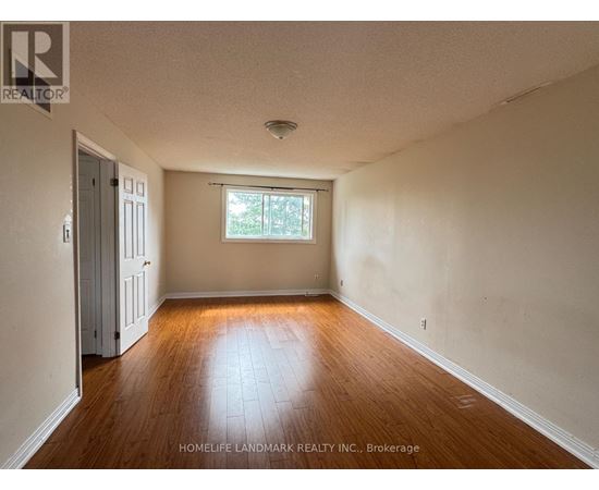 A room with wooden floors and a window with a view of trees.