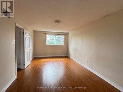 A room with wooden floors and a window with a view of trees.