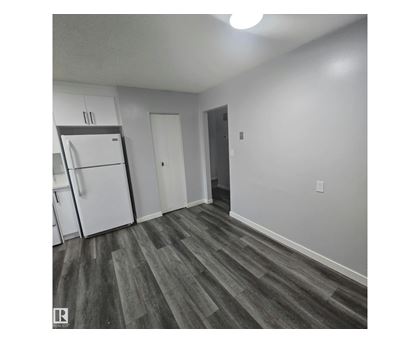 A kitchen with a white refrigerator and a wooden floor.