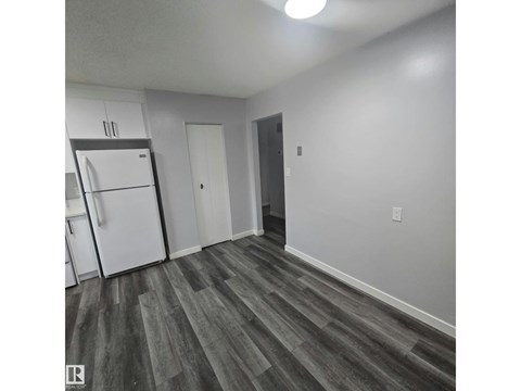 A kitchen with a white refrigerator and a wooden floor.