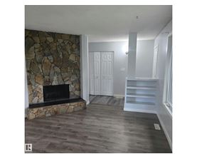 A stone fireplace in a room with wooden floors.