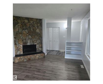 A stone fireplace in a room with wooden floors.