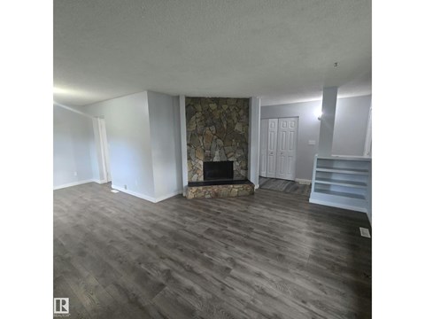 A room with a stone fireplace and wooden flooring.