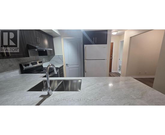 A kitchen with a white counter top and a stainless steel sink.